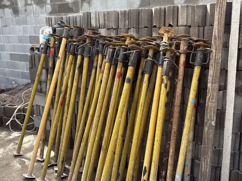 Fila de puntales extensibles de 3,06 m apoyados contra una pared de ladrillo