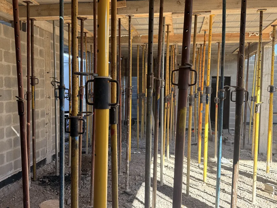 Puntales extensibles amarillos sosteniendo el encofrado de una losa en una casa en construcción
